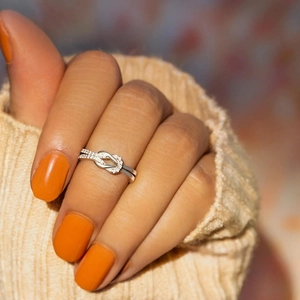 Minimalist silver infinity knot ring with pavé stones shown on model hand