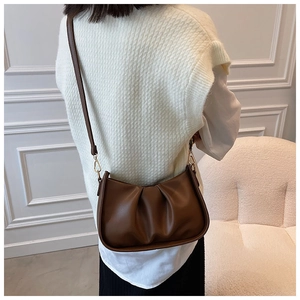 Gros plan d'un sac nuage plissé marron avec crochets dorés et fine bandoulière en cuir