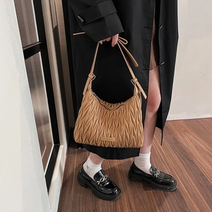 Close-up of camel brown pleated hobo bag featuring vertical stitching and adjustable strap