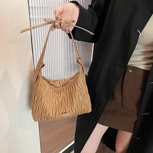 Detail of khaki pleated PU leather handbag with a bow strap held by a model