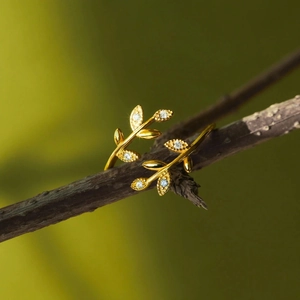 Adjustable gold leaf ring with sparkling diamonds on a natural wooden branch background