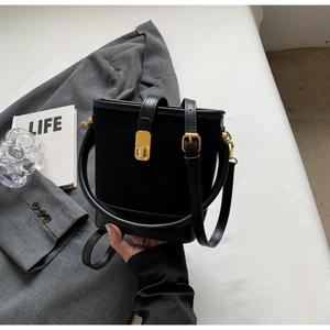 Detail of black suede and leather bucket bag featuring a gold metal twist lock buckle