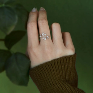 Detail of silver leaf cross ring with sparkling zircons on a model hand close-up