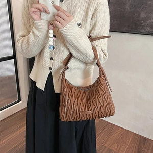 Detail of brown pleated leather shoulder bag showing matelasse texture and strap