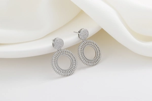 Macro detail of silver geometric earrings with micro-pave zircons and gear texture