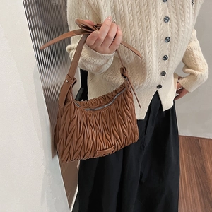 Detail of dark brown pleated hobo bag with textured crescent shape and leather strap