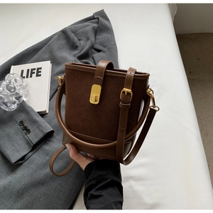 Detailed view of the brown bucket bag showing suede texture and golden metal twist lock