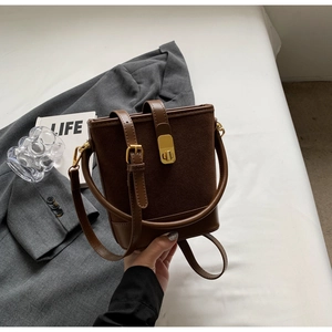 Detail of vintage brown bucket bag showing gold buckles and textured leather contrast