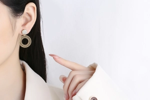 Macro view of gold hoop earrings with pavé crystals on white blazer model