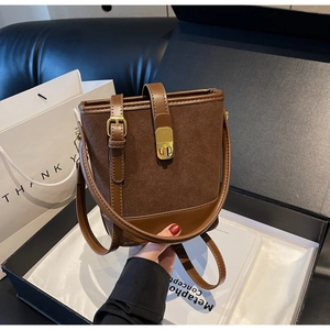 Detail of vintage brown bucket bag with gold clasp, smooth leather and suede texture