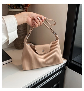 Vue détaillée de la texture plissée verticale et des anneaux argentés du sac beige