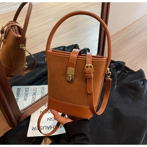 Detail of a brown bucket bag showing suede and smooth leather textures with gold hardware