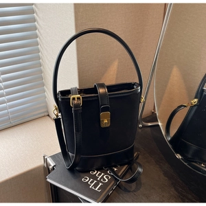 Detail of retro black bucket bag with gold clasp and hard handle on art books
