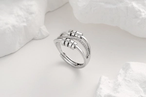 Detail of silver spinner ring with sliding beads and pavé stones on white marble