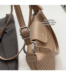 Détail de la boucle métallique réglable et texture plissée verticale sur un sac kaki
