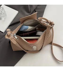 Vue de dessus du sac plissé beige ouvert montrant l'intérieur spacieux et les accessoires