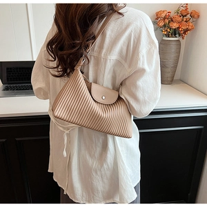 Détail de la texture plissée verticale et boucle argentée sur le sac à bandoulière beige