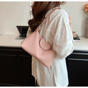 Détail de la texture plissée rose et de la boucle magnétique argentée d'un sac à main