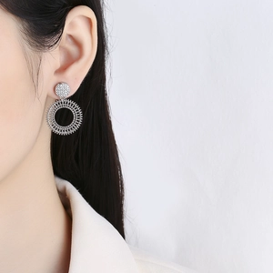 Minimalist silver round zircon earrings with woven hollow circle pendant worn on ear