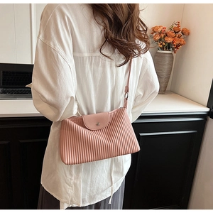 Sac à bandoulière rose plissé porté avec une chemise blanche dans un décor de bureau