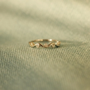 Detailed macro view of gold wavy ring with five sparkling zircons on blue fabric