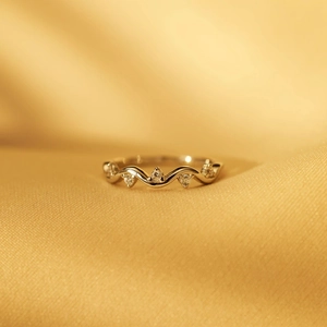 Macro detail of wave patterned ring with sparkling zircon inlays on golden silk