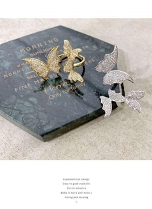 Detailed view of gold and silver butterfly rings with pavé zircon on green marble