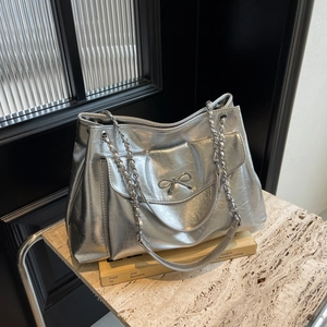 Metallic silver tote bag with crinkled texture, bow buckle, and chain strap
