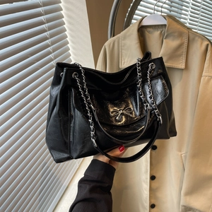 Large black patent leather tote bag with silver metal bow and chain strap design