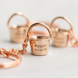 Macro view of rose gold bucket keychain with polished finish and FUCKIT BUCKET engraving