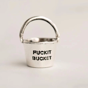Macro shot of silver metal bucket pendant engraved with FUCKIT BUCKET text