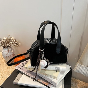 Detail of black matte bowling bag with ANDI logo, baseball charm, and crossbody strap