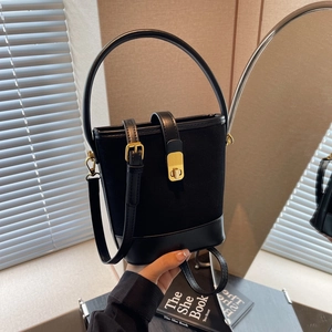Retro black bucket bag in suede and leather mix with gold hardware held by hand