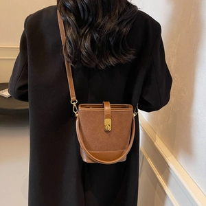 Brown vintage suede bucket bag with gold clasp and leather strap shown on model back
