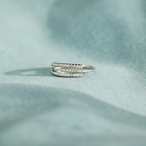 Détail d'une bague triple en argent sertie de zircons sur un velours menthe doux