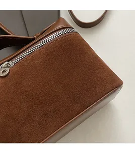 Detail of brown suede crossbody bag showing smooth silver zipper and precise stitching