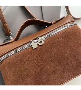 Detail of dual silver zippers on brown leather and suede crossbody bag showing smooth texture