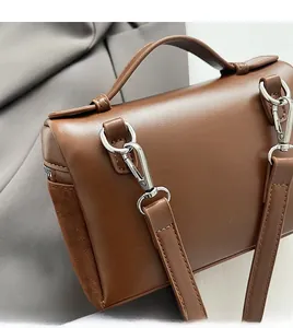Detail of brown shoulder bag showing synthetic and suede stitching with silver metal hooks