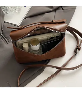 Detail view of brown leather crossbody bag interior showing phone and cosmetic capacity