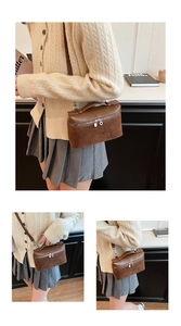 Detailed view of brown suede and leather box bag with top handle and silver zippers