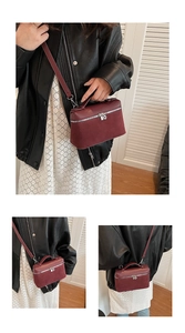 Detail view of burgundy crossbody square bag showing matte texture and double silver zippers