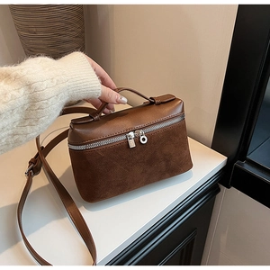 Detail of a brown two-tone crossbody bag featuring faux leather and suede texture contrast