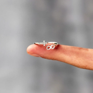 Détail de la bague en argent s925 avec croix et infini sertie de zircons sur un doigt