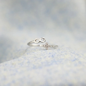 Détail d'une bague infini en argent avec croix en zircon sur tissu bleu clair