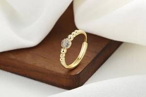 Macro detail of a gold beaded open ring featuring a sparkling zircon pavé sphere