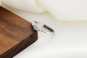 Macro detail of silver adjustable bubble ring with sparkling zircon pavé on silk background