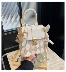 Détail du sac bandoulière matelassé blanc avec boucle dorée et breloque lapin