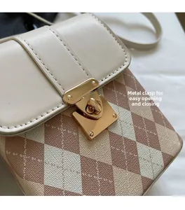 Détail du fermoir doré sur sac à rabat matelassé marron et coutures en cuir beige