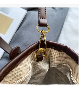 Detailed view of golden buckle and beige woven fabric with herringbone lining