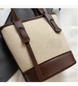 Detail of contrast bucket bag showing coarse canvas texture and smooth brown leather stitching